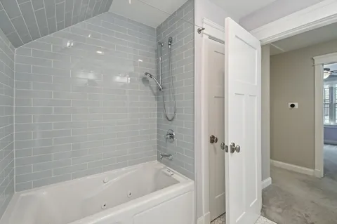 Remodeled bathroom with light blue glass subway tile and a built-in jetted tub