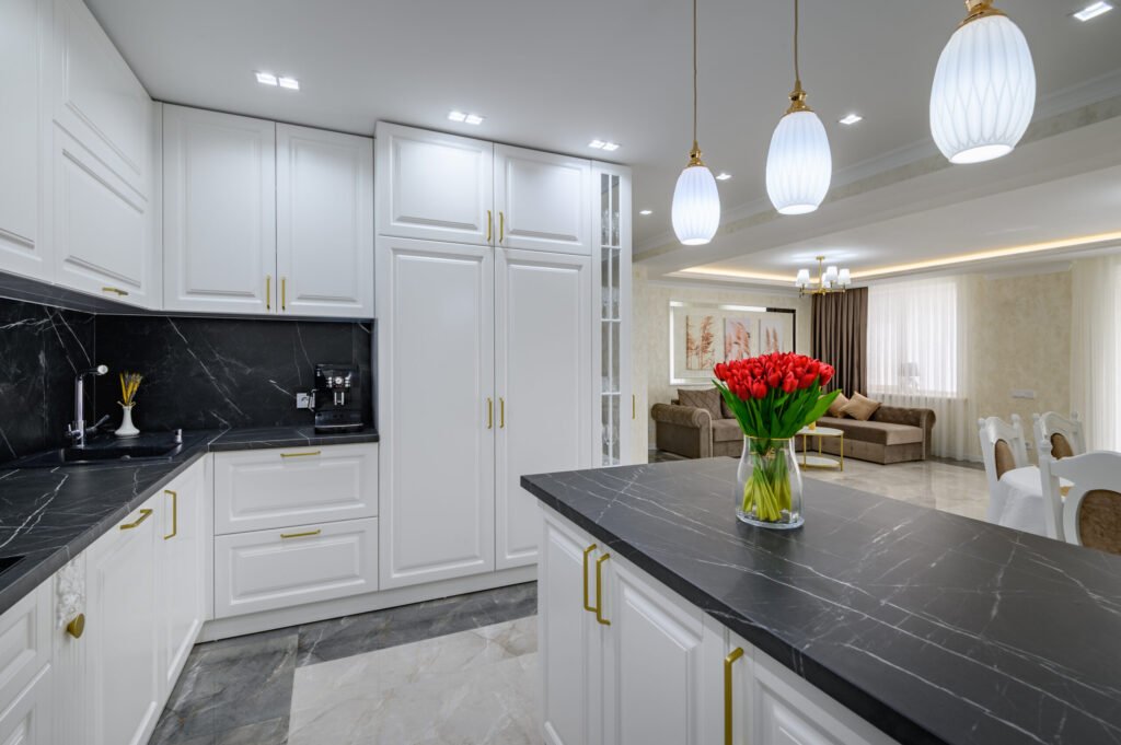 Large black and white expensive well-designed modern kitchen in studio interior black marble countertop